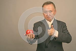 Portrait of mature Asian businessman with apple