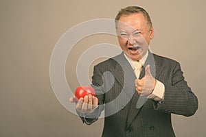 Portrait of mature Asian businessman with apple