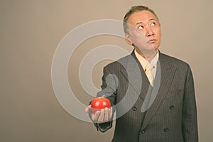 Portrait of mature Asian businessman with apple