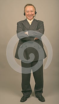 Portrait of mature Asian businessman as call center representative