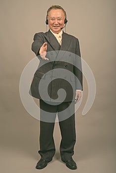 Portrait of mature Asian businessman as call center representative