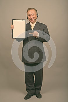 Portrait of mature Asian businessman as call center representative