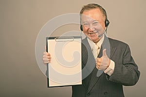 Portrait of mature Asian businessman as call center representative