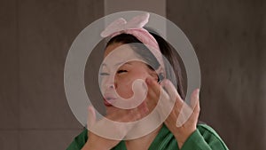 Portrait of mature Asian woman doing beauty treatment and answering phone call