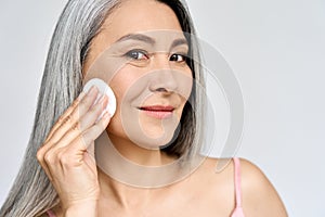 Portrait of mature Asian woman holding cotton pad doing everyday routine.