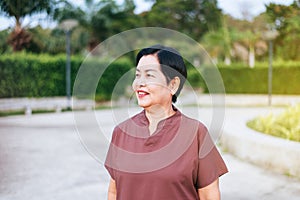 Portrait of mature asian woman standing at public park,Happy and smiling,Senior care insurance concept