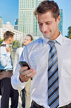 Portrait of mature attractive businessman smiling while using smartphone after work