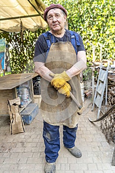 Portrait of mature blacksmith. Iron worker in workshop outdoors