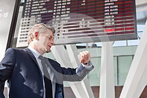 Portrait of mature businessman checking time on his watch while waiting in the airport