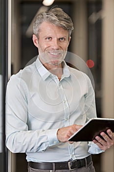 Portrait of mature businessman with digital tablet at office