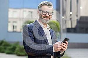 Portrait of a mature businessman, a gray-haired experienced man smiling and looking at the camera, a boss in a business