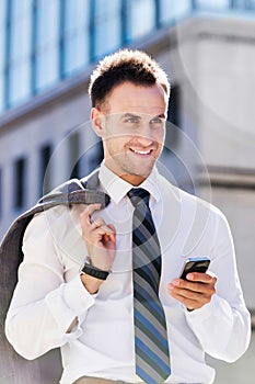 Portrait of mature businessman using smartphone while walking on pavement after work