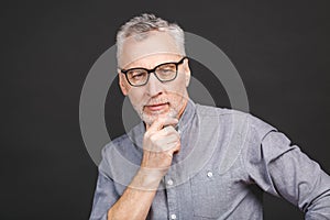 Portrait of a mature businessman wearing glasses  against black background. Happy senior man looking at camera with copy