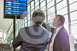 Portrait of mature businessmen looking at their flight on monitor in airport