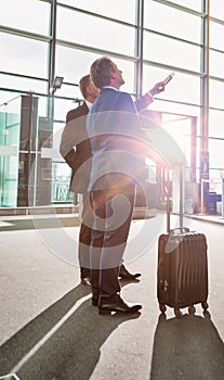 Portrait of mature businessmen looking at their flight on monitor in airport