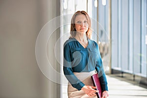 Portrait of Mature businesswoman standing while holding document in office hall