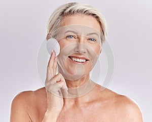 Portrait of a mature caucasian woman using a cotton pad to remove makeup during a selfcare grooming routine. Older model