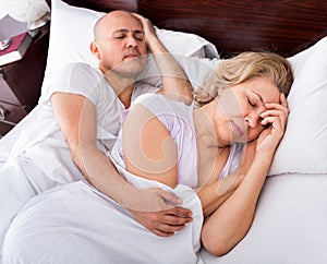 Portrait of mature couple napping in bed
