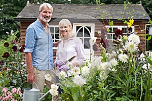 Portrait Of Mature Couple Working In Flower Beds In Garden At Home