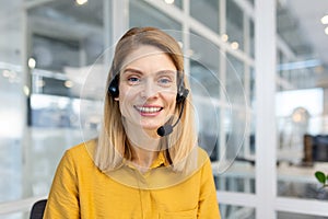 Portrait of mature female customer service worker, mature business woman with video call headset smiling and looking at