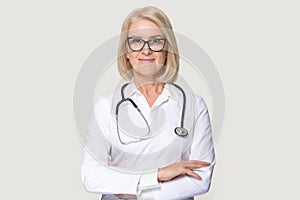 Portrait of mature female doctor isolated on grey background photo