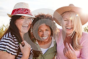 Portrait Of Mature Female Friends Walking Through Field On Camping Vacation