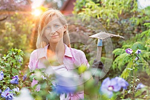 Portrait of mature female gardener holding fork rake