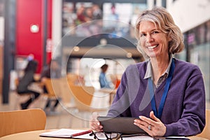 Portrait Of Mature Female Teacher Or Student With Digital Tablet Working At Table In College Hall