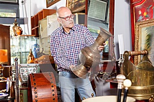 Portrait of mature man choosing vintage goods at antiques shop