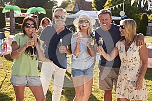 Portrait Of Mature Friends Enjoying Drinks At Summer Garden Fete photo