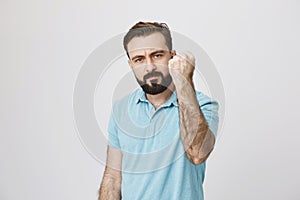 Portrait of mature handsome looking male holding his hand up wearing blue shirt. Man shows gesture of support to his