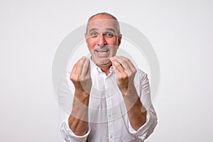 Portrait of mature handsome man in white shirt showing italian gesture