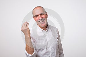 Portrait of mature handsome man in white shirt showing italian gesture