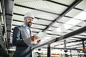 A portrait of an industrial man engineer with tablet in a factory.