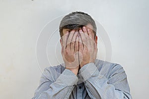 Portrait of a Mature male in a state of psychological stress against a light wall. A male with a short haircut and graying hair