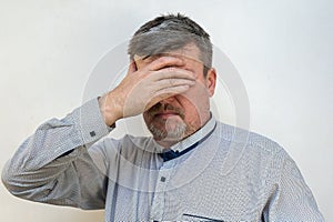 Portrait of a Mature male in a state of psychological stress against a light wall. A male with a short haircut and graying hair