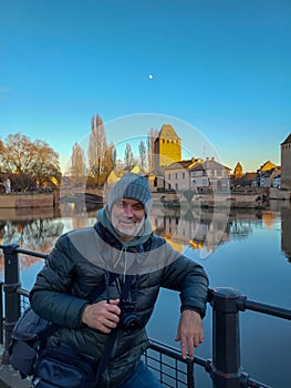 Portrait of mature man with camera at the medieval bridge Ponts Couverts and barrage Vauban