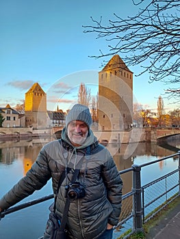 Portrait of mature man with camera at the medieval bridge Ponts Couverts and barrage Vauban