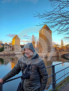 Portrait of mature man with camera at the medieval bridge Ponts Couverts and barrage Vauban