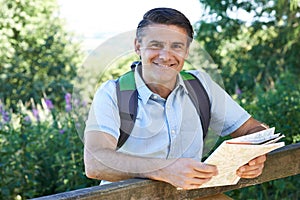 Portrait Of Mature Man Hiking In Countryside Looking At Map