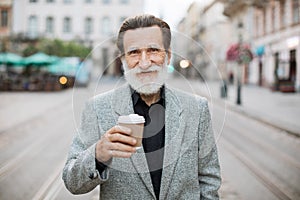 Portrait of mature man holding cup of coffee outdoors
