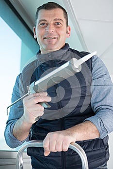 portrait mature man holding sealant gun