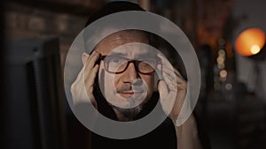 Portrait of mature man at home in dark room wearing glasses