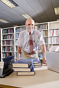 Portrait of mature man at library with textbooks