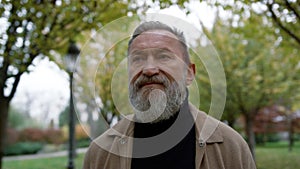 Portrait of mature man with long grey beard outdoors. Old man going.