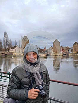 Portrait of mature man at the medieval bridge Ponts Couverts and barrage Vauban, evening scene of Strasbourg