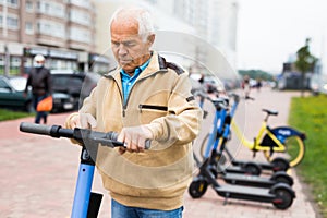 Portrait of mature man posing with electric scooter outdoor