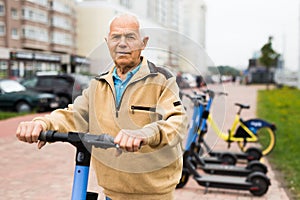 Portrait of mature man posing with electric scooter outdoor