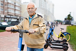 Portrait of mature man posing with electric scooter outdoor