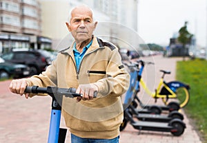 Portrait of mature man posing with electric scooter outdoor